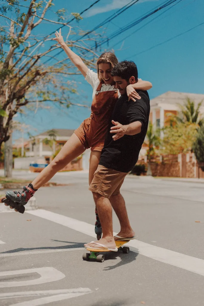Ein Paar, dass mit einen Skateboard und Inline-Skatern die Sonne genießt.